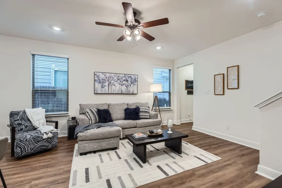 Duplex living room with a gray sectional sofa, dark coffee table and ceiling fan